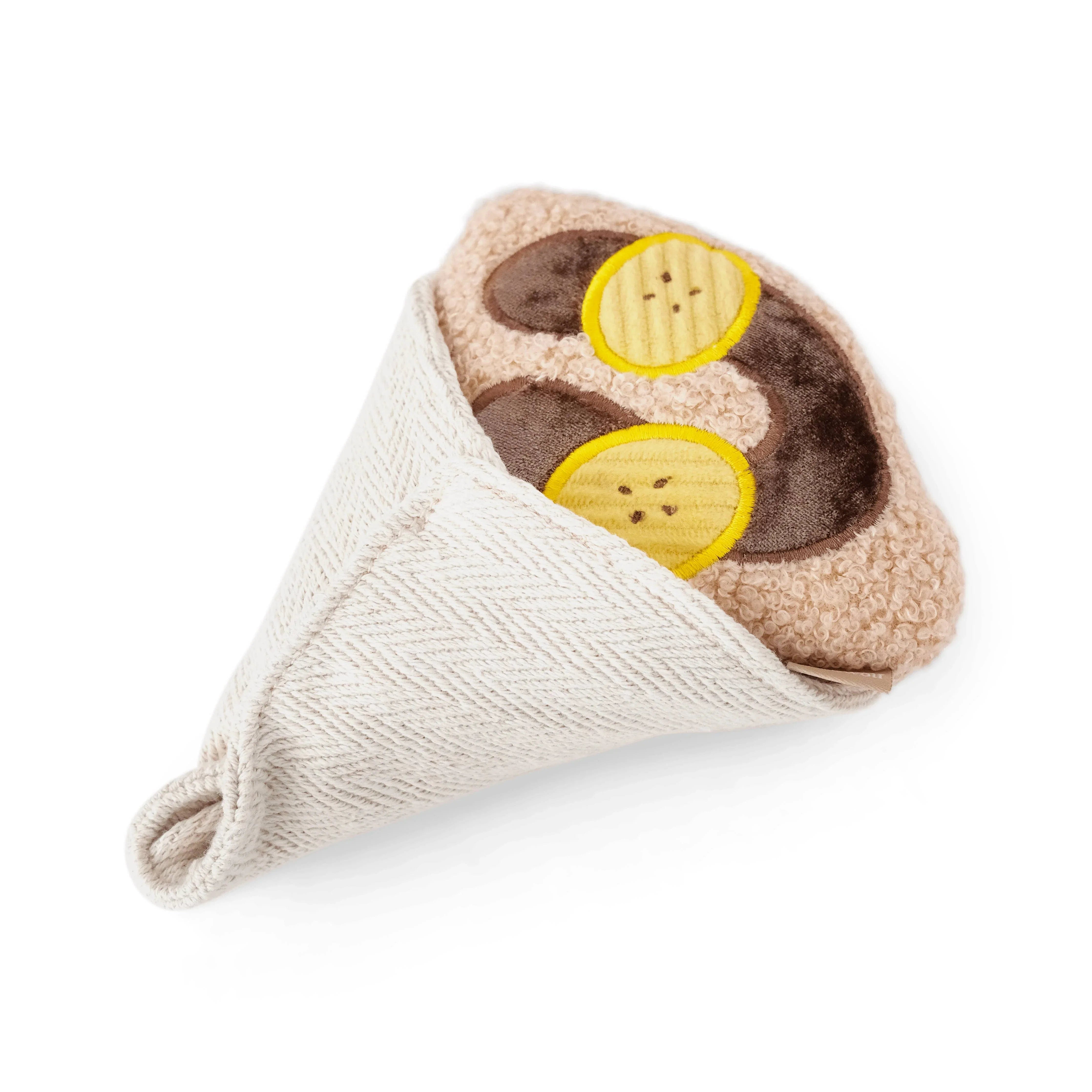Gefaltetes Retourenpaket aus beigem Stoff mit braunen Applikationen und gelben Knopfmotiven auf weißem Hintergrund mit Lambwolf Crêpe Schnüf
