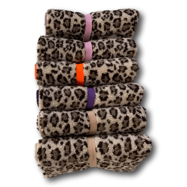 Fünf gefaltete Decken mit Leopardenmuster, jede mit einem farblich unterschiedlichen Band in Lila, Hellrosa, Orange, Violett und Beige fixie