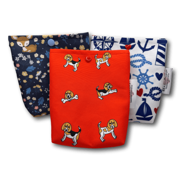 Drei kleine quadratische Taschen aus robustem Stoff mit Aufhängelaschen am oberen Rand. Eine Tasche ist rot mit mehreren kleinen Beagle-Hund