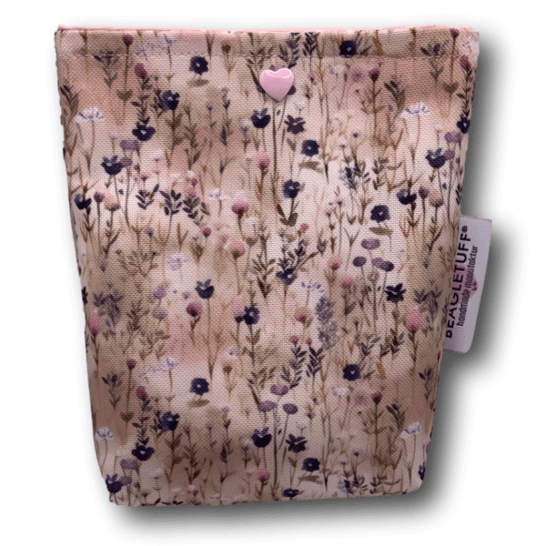 Beigefarbener eckiger Taschenkrümmer mit floralem Muster in Rosa- und Blautönen auf hellem Grund, oben ein kleiner rosa Herz-Knopf, seitlich