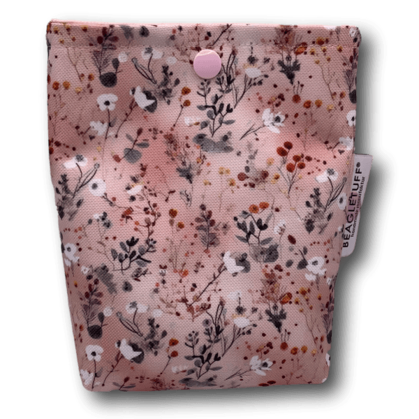 Rosa Stofftasche mit floralem Muster in verschiedenen Farben und einem Druckknopf zum Verschließen, mit einem weißen Beagletuff-Etikett an d